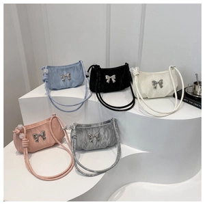 Detail of five colorful pleated bow shoulder bags with metallic ribbon on white steps