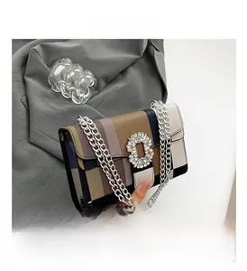 Detail of colorful striped crossbody bag with rhinestone buckle and silver chain