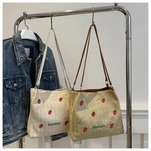 Detail van twee strooien shopper tassen met aardbeiborduurwerk en fashion-tekst