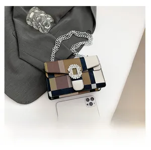 Detail of color-block chain bag with rhinestone buckle on gray suit background