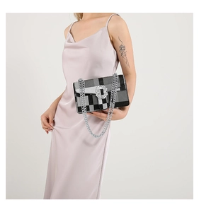 Detail of crossbody bag with black grey checkered pattern and rhinestone buckle on dress