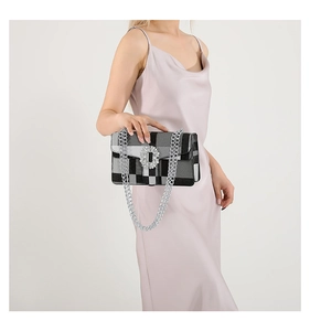 Detail of checkered crossbody bag with oversized rhinestone buckle and silver chain strap