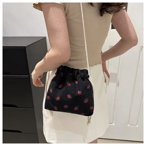 Détail du sac seau en velours côtelé à motif fraises rouges avec bandoulière tissée