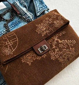 Detail of vintage corduroy crossbody bag with floral patterns and metal twist lock