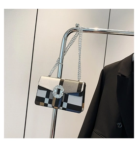 Macro detail of patchwork crossbody bag featuring a crystal-encrusted round buckle and chain