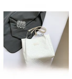 Detail of white woven PU tote bag featuring a metal chain strap and fashion label
