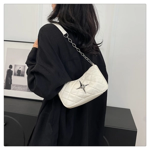 Close-up of white quilted crescent bag with silver star logo and metal chain strap detail