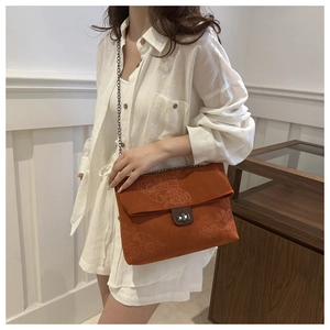 Detail of vintage orange corduroy crossbody bag with embossed patterns and chain strap