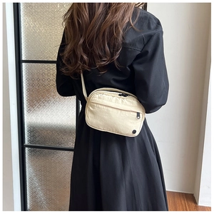Detailansicht einer beigen Nylon-Umhängetasche im minimalistischen Utility-Stil getragen