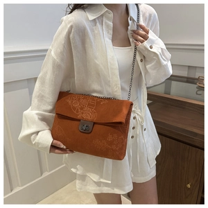 Detail of vintage orange corduroy crossbody bag with floral embroidery and chain strap