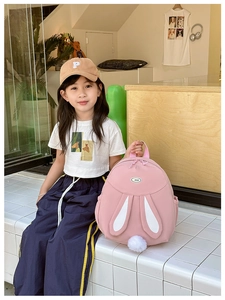 Detalle de mochila rosa para niños con orejas largas de conejo y un suave pompón de peluche