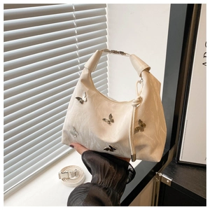 Détail du sac en cuir plissé blanc avec charmes papillon et poignée réglable sur le côté