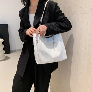 Minimalist white woven leather tote bag with silver chain strap shown on model