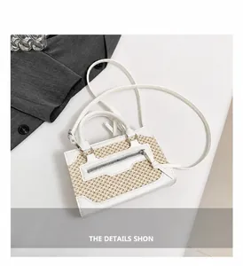 Detail shot of woven texture and leather fringe on a mini white crossbody handbag