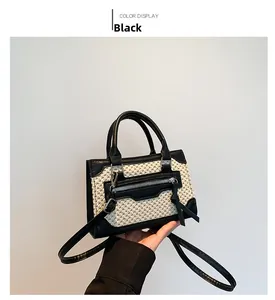 Detail of black and white woven mini handbag with leather trim and front zip pocket