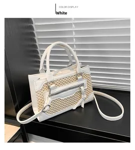 Detail of white woven texture handbag with silver zipper and adjustable shoulder strap