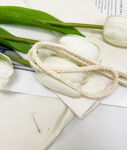 Close-up of the elegant woven shoulder strap on a cream embroidered bucket bag