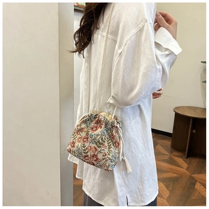 Detail of floral embroidery and drawstring closure on a vintage canvas bucket bag