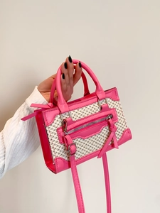 Chic pink leather and straw woven handbag with tassels shown as a stylish crossbody bag