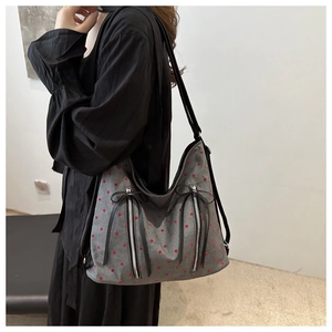 Detailansicht der grauen Canvas-Tasche mit Punkten, Reißverschlüssen und schwarzen Schleifen