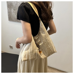 Detail of pleated fabric texture on a champagne tote bag with amber resin pendant