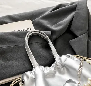 Détail d'un sac à main argenté métallisé avec perles et fermeture plissée élégante