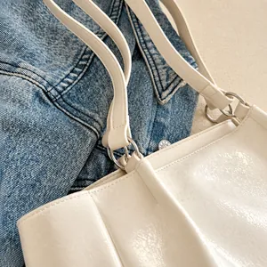 Détail macro du raccord à anneau métallique et coutures renforcées sur le sac crème