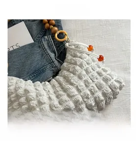 Détail du sac à main plissé blanc avec poignée en bois et cordon à perles orange
