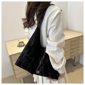 Détail du sac cabas en velours noir avec gaufrage de feuilles et pompon marron