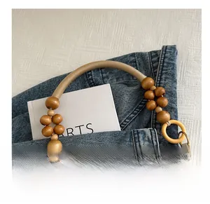 Détail de la bandoulière de sac en perles de bois et anneaux résine sur fond denim