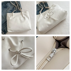 Vue détaillée du sac cabas crème avec nœud, fermeture éclair et texture en cuir PU