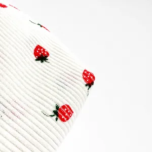 Nahaufnahme der weißen Cord-Stoffstruktur mit süßer roter Erdbeer-Stickerei auf der Tasche