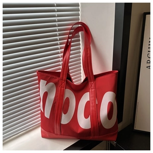 Dettaglio della borsa tote in tela rossa con stampa noco bianca e tracolla robusta