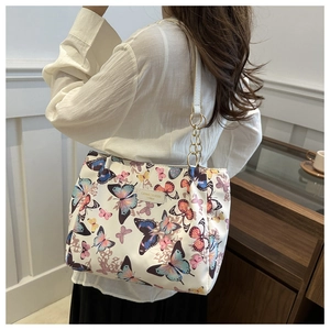 Detail of white butterfly print canvas tote bag with metal logo and chain strap