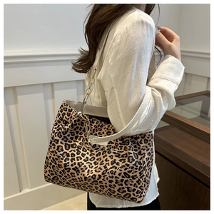 Detailed view of leopard print canvas tote bag with white leather strap and gold chain