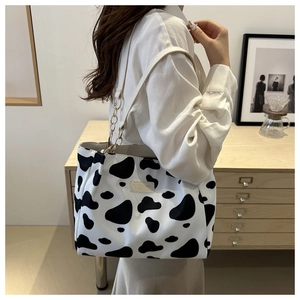Detail of a large capacity cow print tote bag with gold chain and branded leather patch