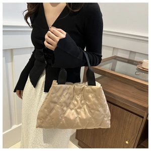 Close-up of beige quilted bucket bag with diamond stitching and black ribbon handle