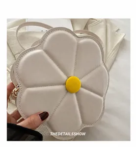 Detail van de crèmewitte bloemvormige crossbodytas met geel hart en gewatteerde bloemblaadjes