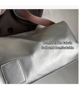 Detalle de bolso plateado metalizado con correa rosa ancha y parche de costura cuadrado