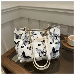 Detail of canvas tote bag with black butterfly print and gold chain strap decoration