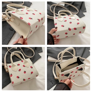 Detail der weißen Cord-Tasche mit roten Erdbeer-Stickereien und Doppelriemen