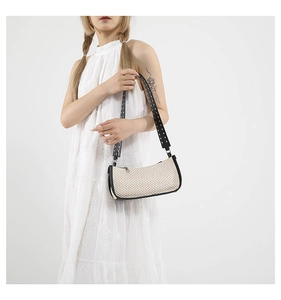Dettaglio borsa sottobraccio intrecciata beige con tracolla nera e borchie argentate