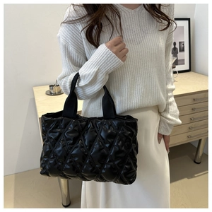 Détail d'un sac cabas matelassé noir avec coutures en losanges porté par un mannequin