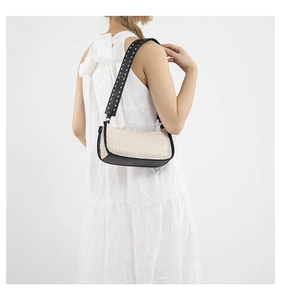 Dettaglio di borsa a mezzaluna intrecciata beige con tracolla larga in pelle nera e borchie