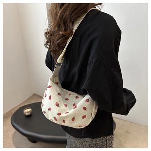 Detalle de bolso hobo de pana blanco roto con bordado de fresas y correa ancha