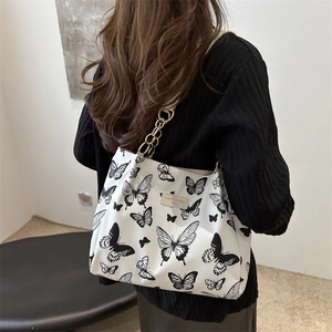 White canvas tote bag with black butterfly prints and elegant gold metal chain straps