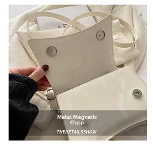Dettaglio delle doppie chiusure magnetiche sulla borsa in pelle bianca effetto marmo