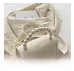Dettaglio della borsa a tracolla in pelle bianca con elegante manico di perle