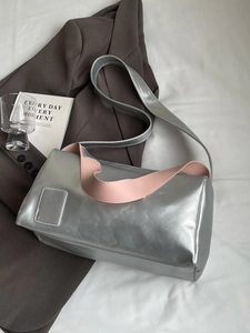 Minimalist silver metallic shoulder bag with pink leather handles in a stylish setting