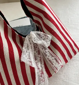 Detalle del bolso de lona a rayas rojas y blancas con lazo de encaje blanco y forro negro
